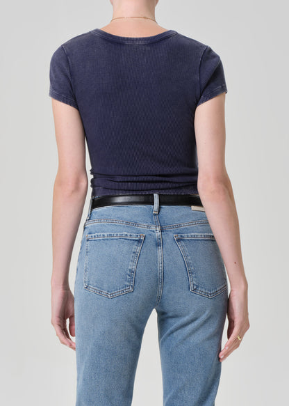 Person wearing a navy blue t-shirt and light blue jeans on a plain background