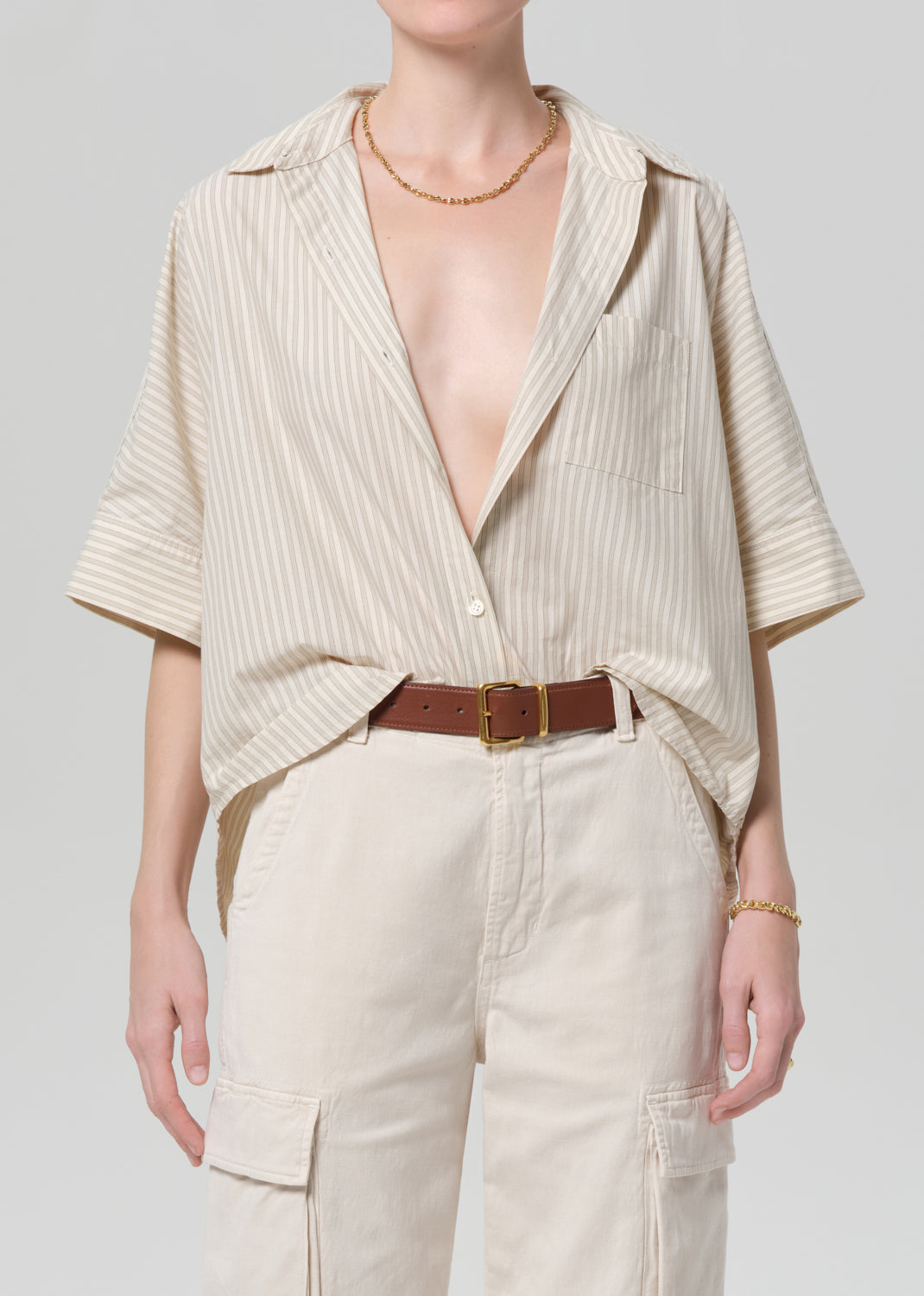 Person wearing a beige ribbed top and pants with a plain background