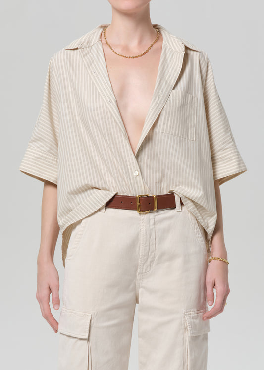 Person wearing a beige ribbed top and pants with a plain background