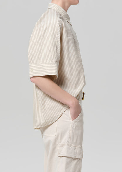 Person wearing a beige ribbed shirt and pants on a light gray background
