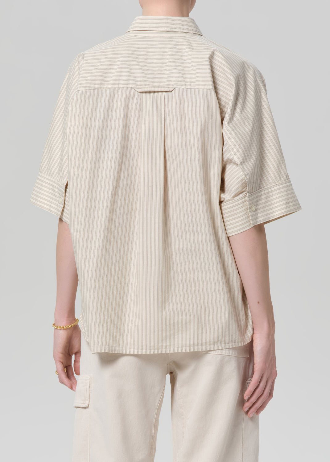 Person wearing a beige ribbed shirt and pants on a gray background