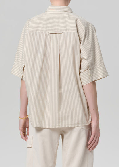 Person wearing a beige ribbed shirt and pants on a gray background