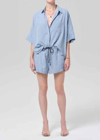 Person wearing a blue striped shirt and matching shorts on a grey background