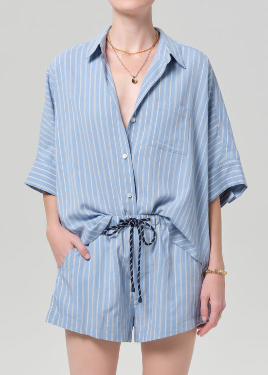Person wearing a blue striped shirt and matching shorts on a grey background