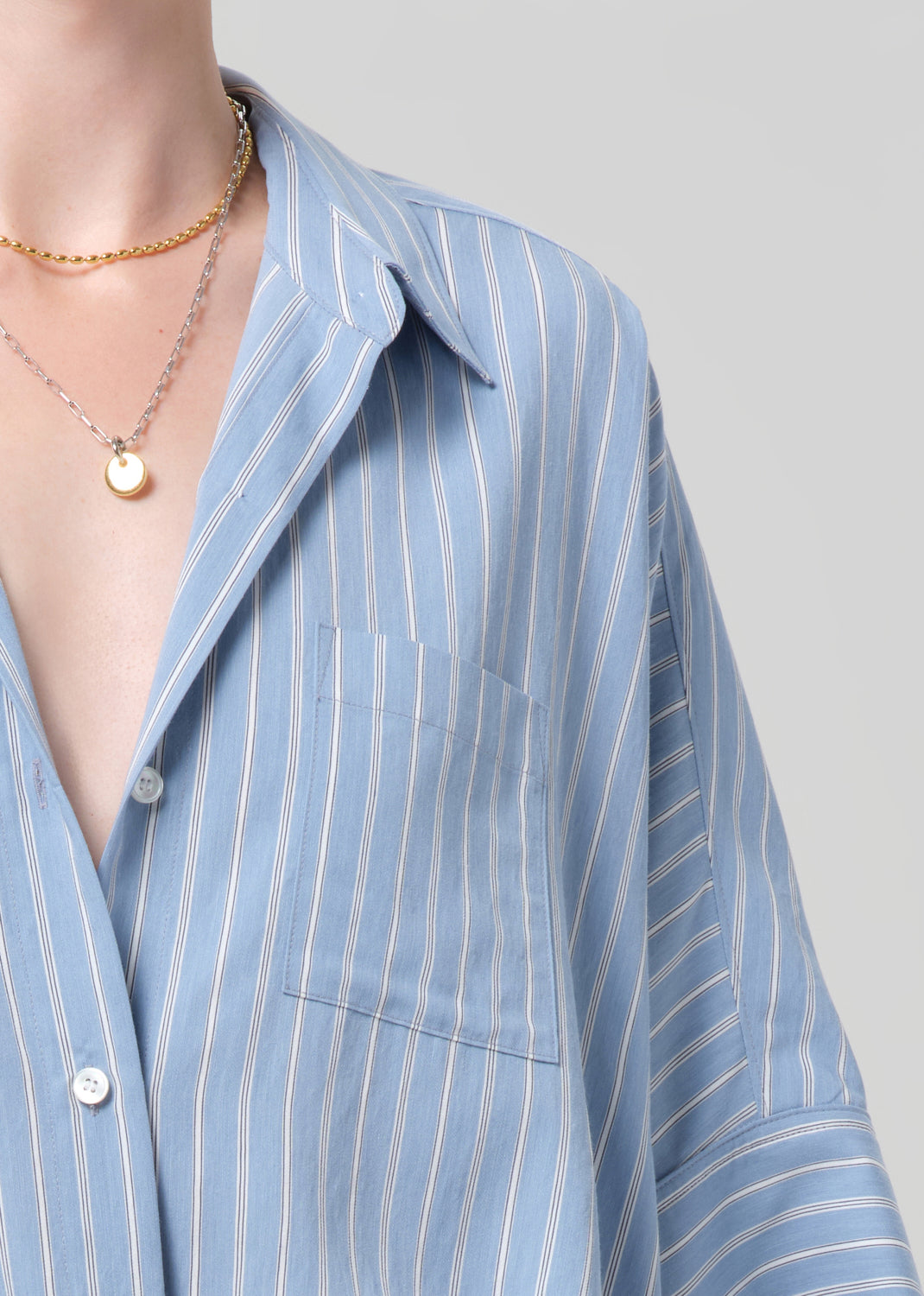 Person wearing a blue striped shirt and matching shorts on a grey background