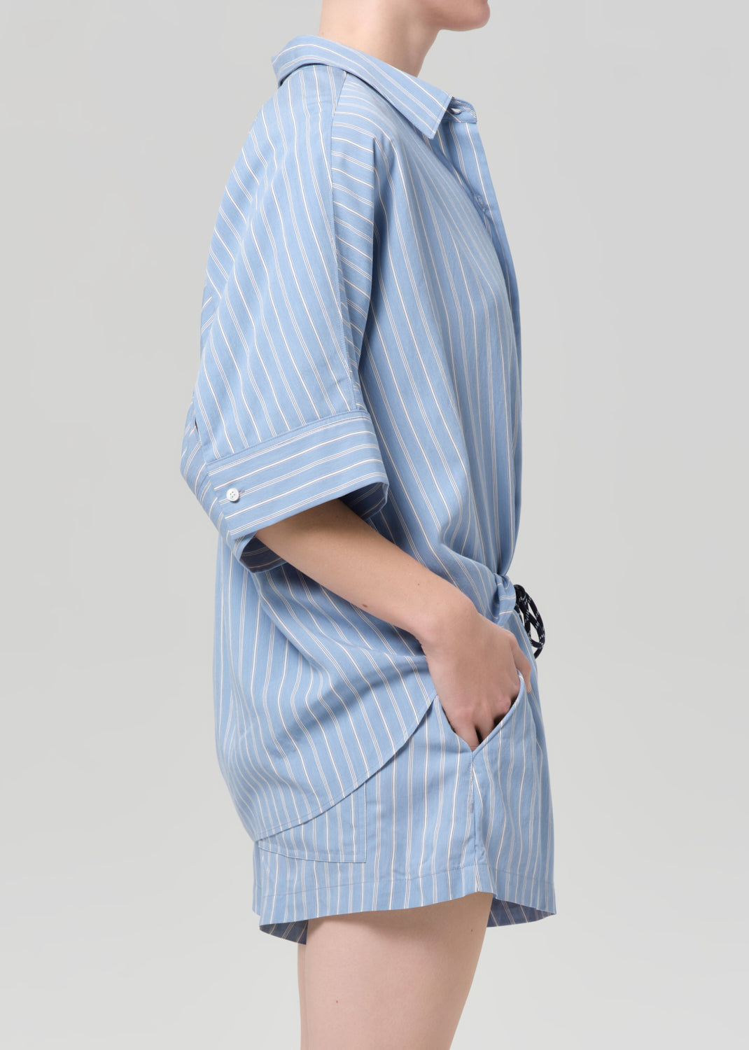 Person wearing a blue striped shirt and matching shorts on a grey background