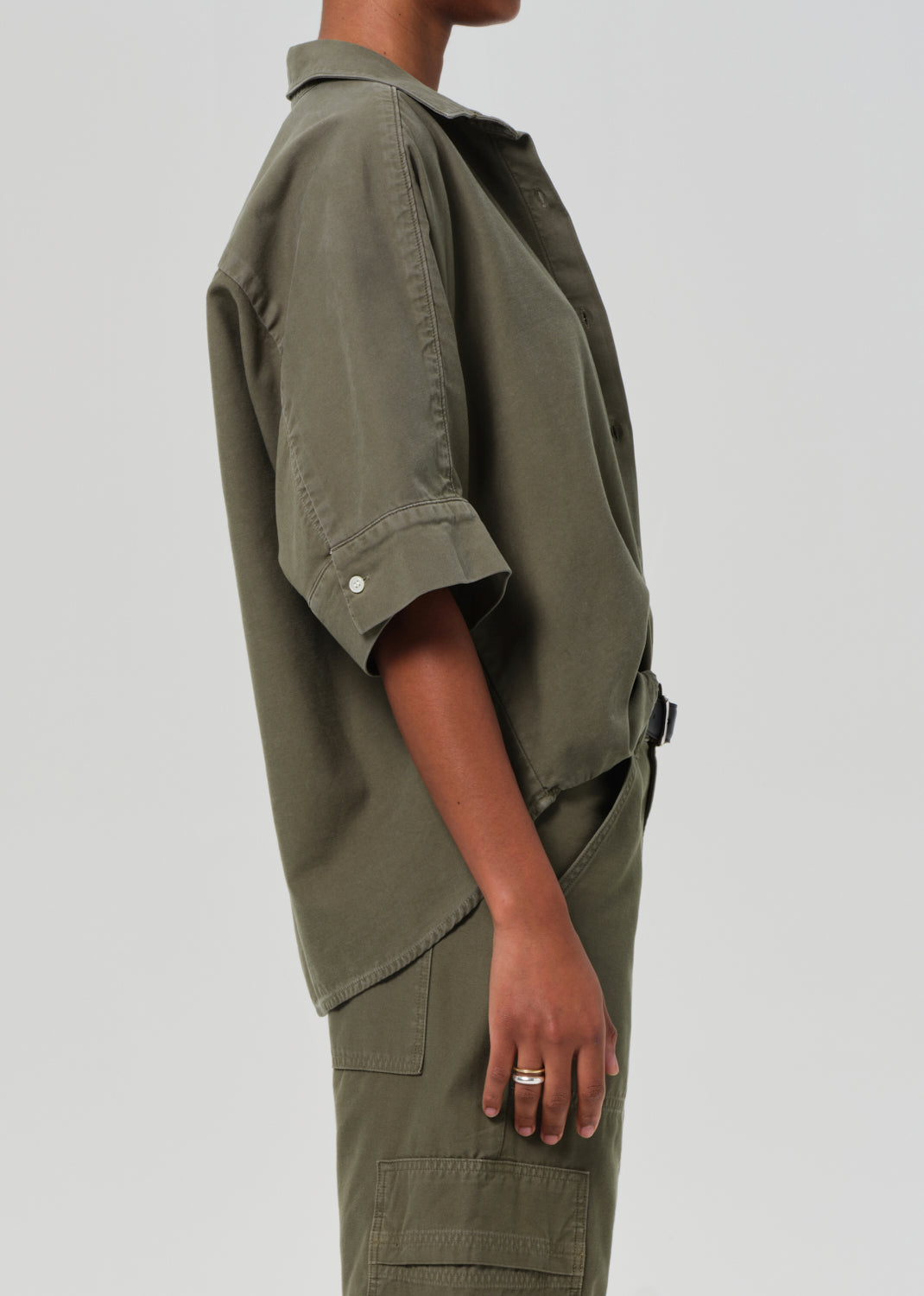 Person wearing a green utility-style outfit on a plain background