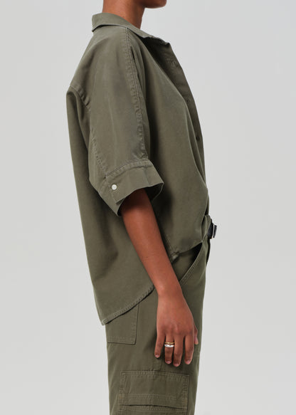 Person wearing a green utility-style outfit on a plain background