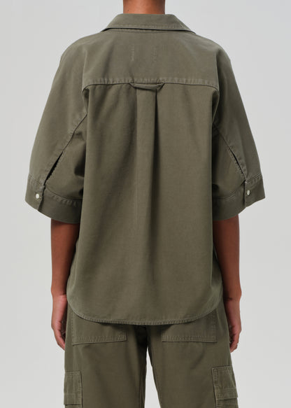 Person wearing an olive green shirt and pants on a white background