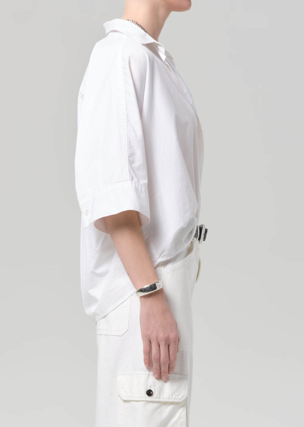 Person wearing a white shirt with white pants on a plain background