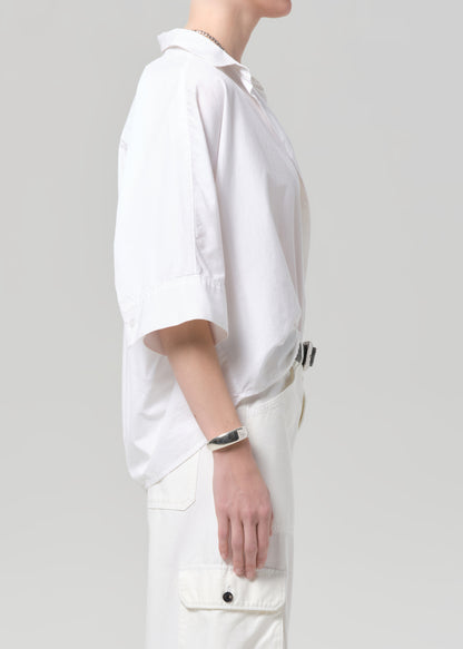 Person wearing a white shirt with white pants on a plain background