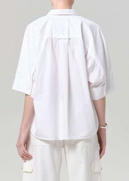 Person wearing a white shirt and pants on a plain background