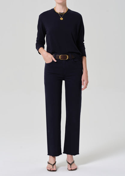 Person wearing a navy shirt and dark pants with a belt on a light gray background