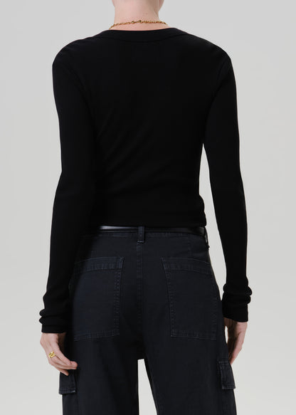 A person shown from the back wearing a fitted black long-sleeve top and dark cargo-style pants against a grey background.