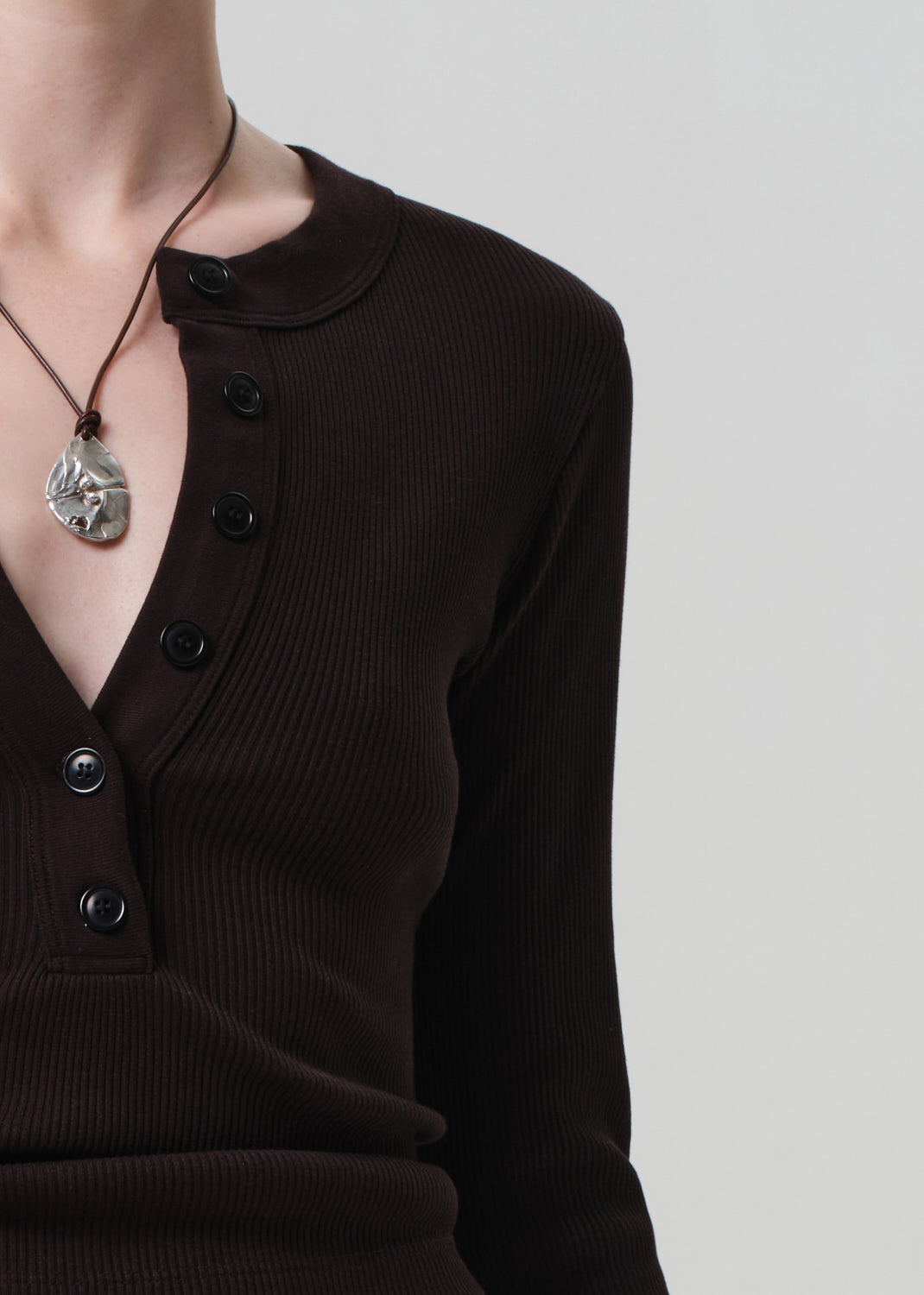 Person wearing a brown long-sleeve top on a light gray background