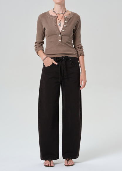 Person wearing a brown ribbed sweater and brown pants on a plain background