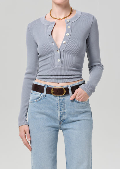 Person wearing a gray long-sleeve top and light blue jeans on a plain background