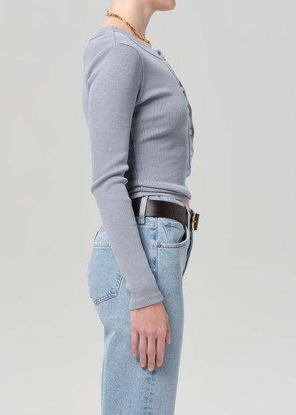 Person wearing a gray long-sleeve shirt and light blue jeans on a plain background