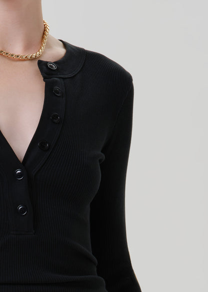 Person wearing a black long sleeve henley top on a grey background