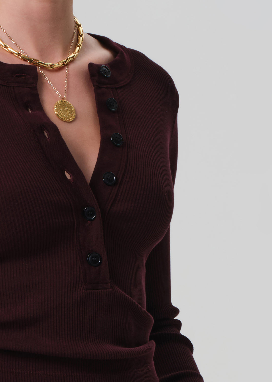 Brown button-up shirt with gold necklace on a plain background