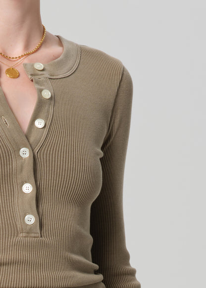 Brown ribbed top with buttons on a plain background