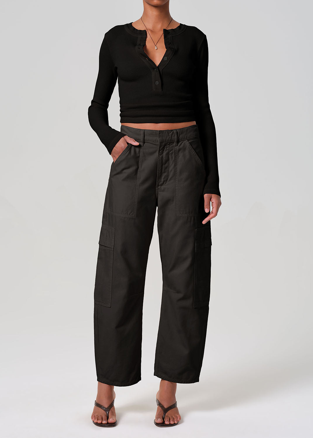 Person wearing a black long-sleeve top and black pants on a white background