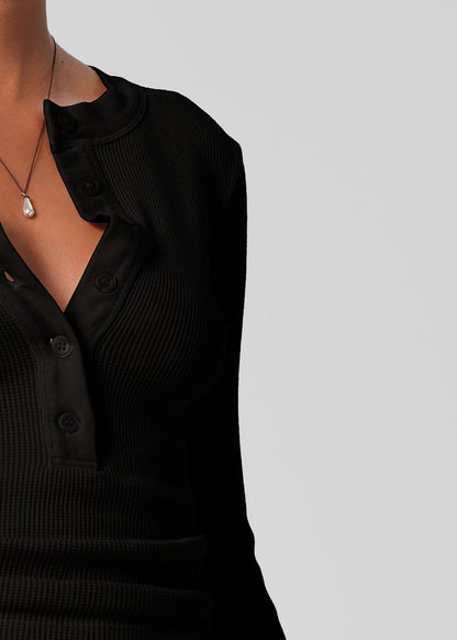 Black ribbed sweater worn by a person on a light gray background