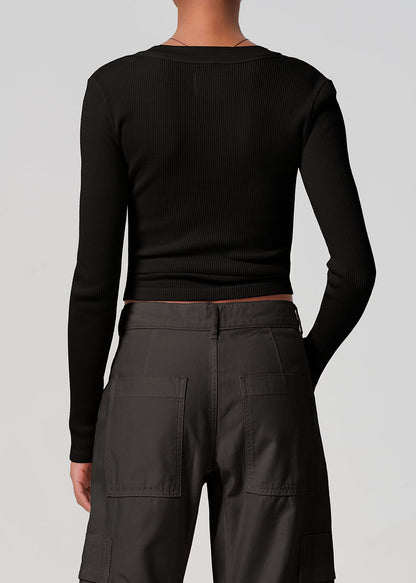 Person wearing a black long-sleeve top and dark cargo pants on a light gray background