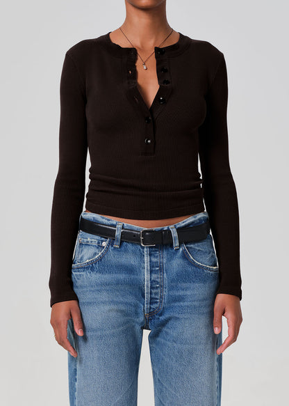 Person wearing a brown long-sleeve top and blue jeans on a gray background