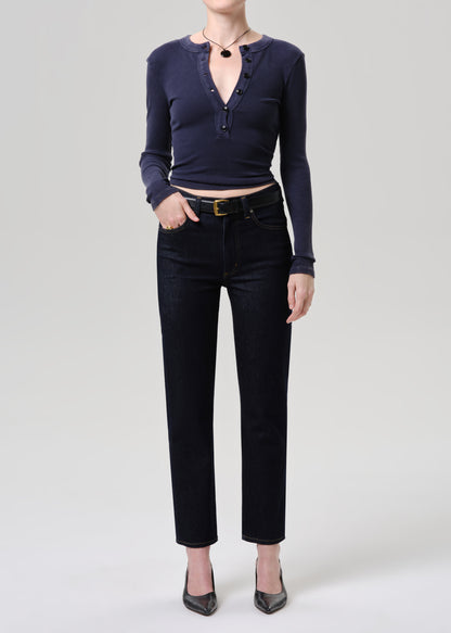Person wearing a navy long-sleeve top and black pants on a grey background.