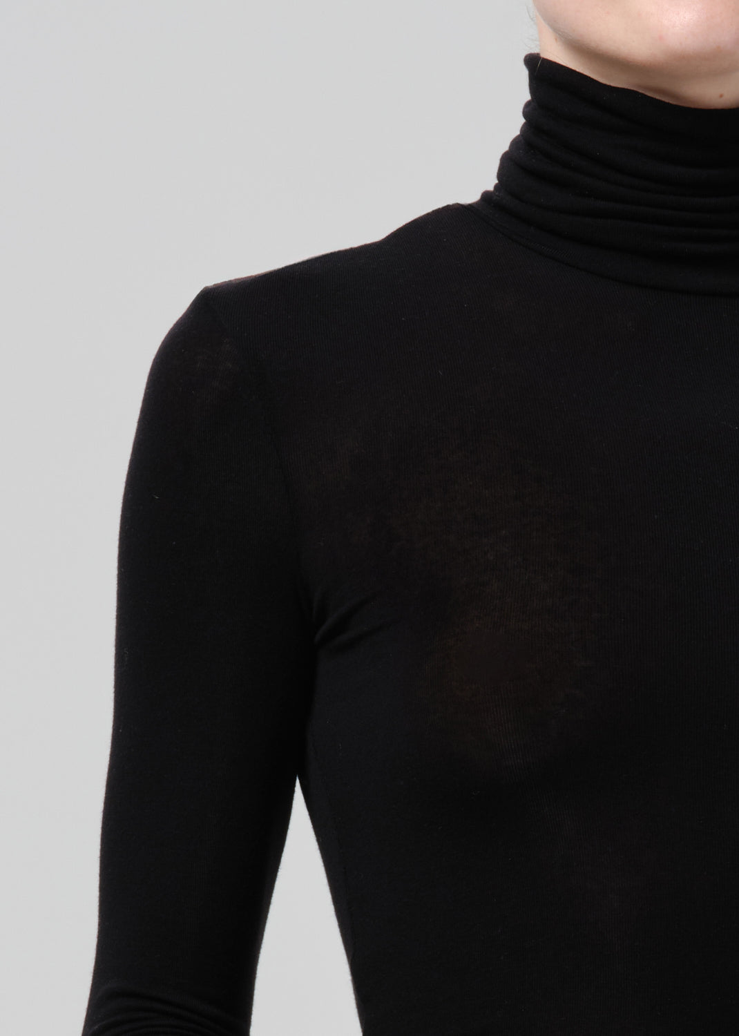 Close-up of a black fitted turtleneck on a grey background