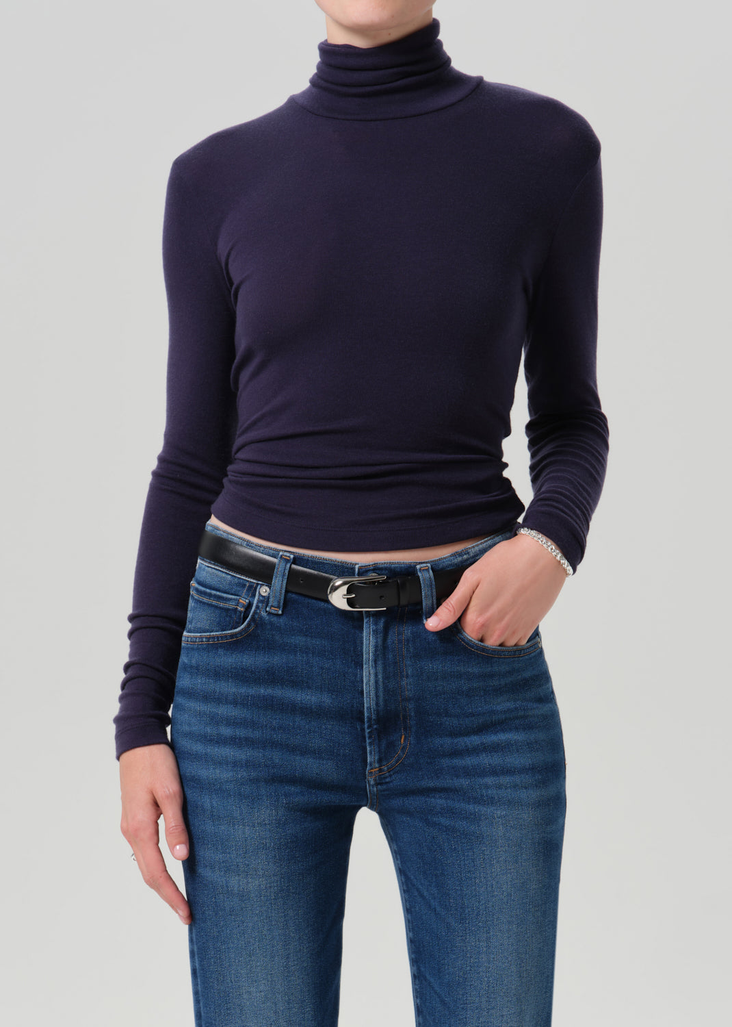 Person wearing a navy long sleeve turtleneck on a grey background