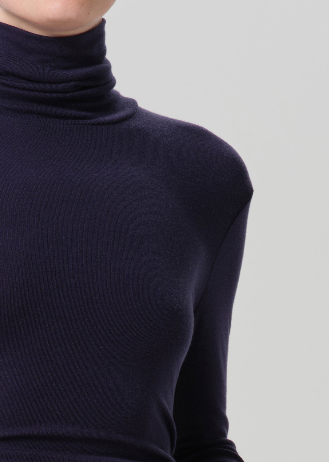 Close-up of a navy long sleeve turtleneck on a grey background