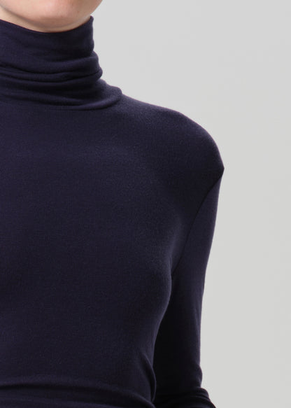 Close-up of a navy long sleeve turtleneck on a grey background