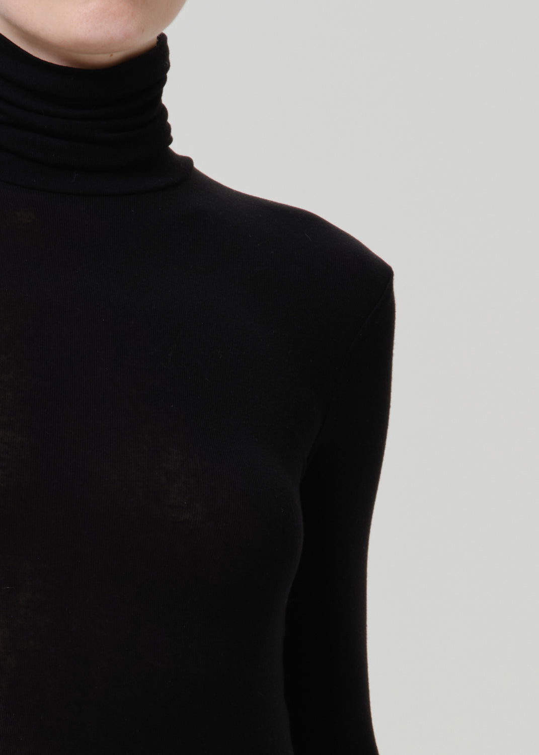 Close-up of a black turtleneck top on a grey background.