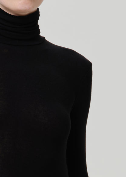 Close-up of a black turtleneck top on a grey background.