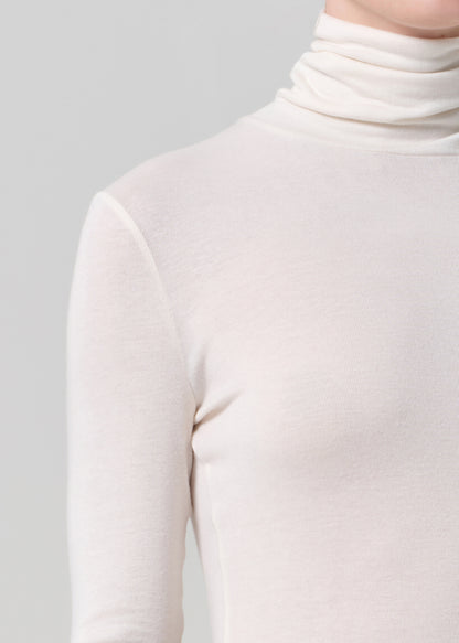 Person wearing a white turtleneck on a gray background