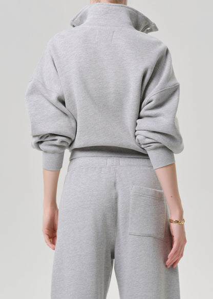 A person shown from the back wearing a light grey heathered sweatshirt and matching sweatpants against a plain light grey background.