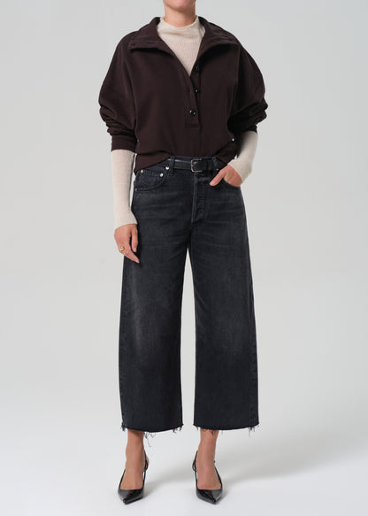 Person wearing a dark brown sweatshirt , white sweater, and black jeans on a white background