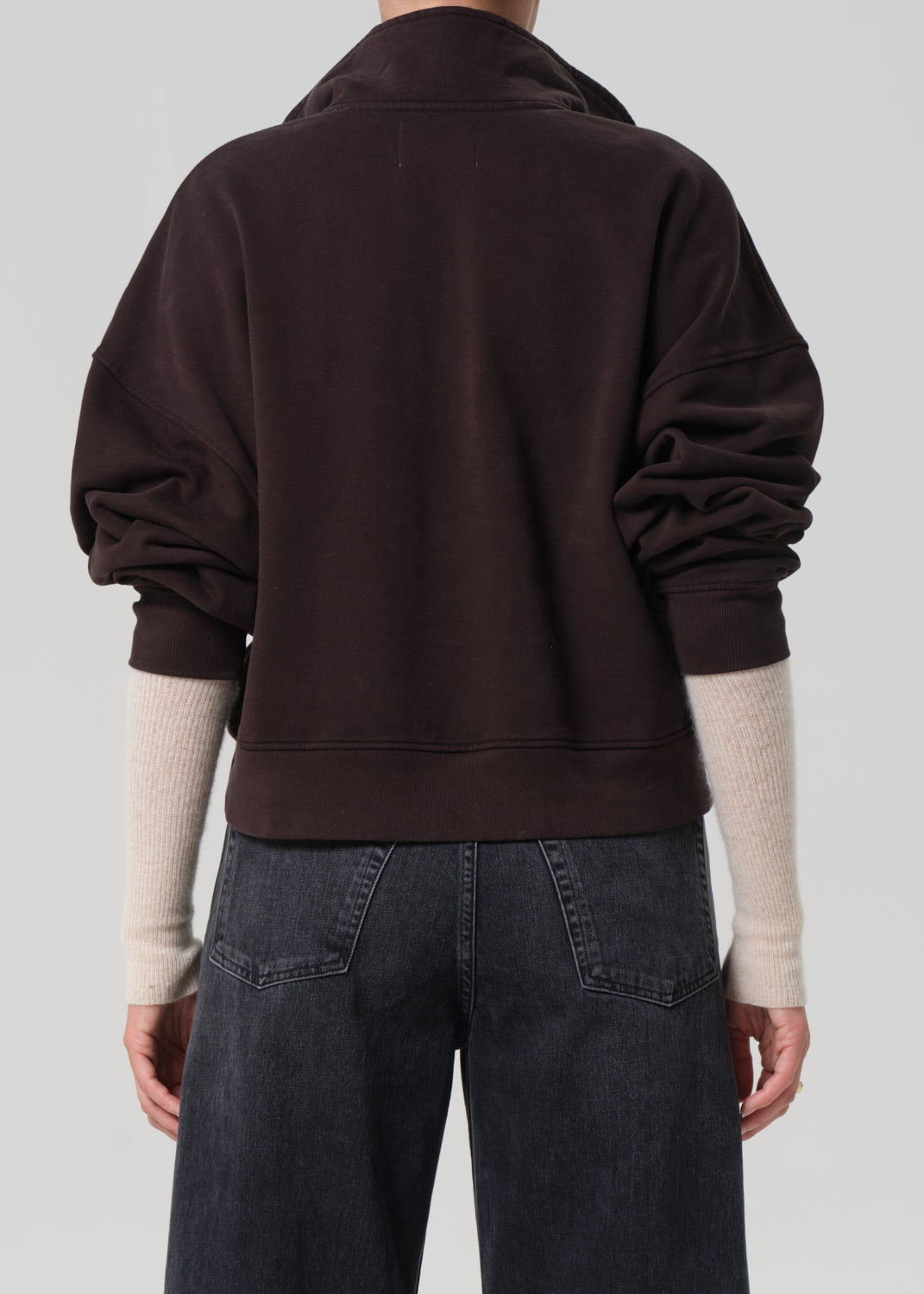 Person wearing a dark brown sweatshirt on a plain background