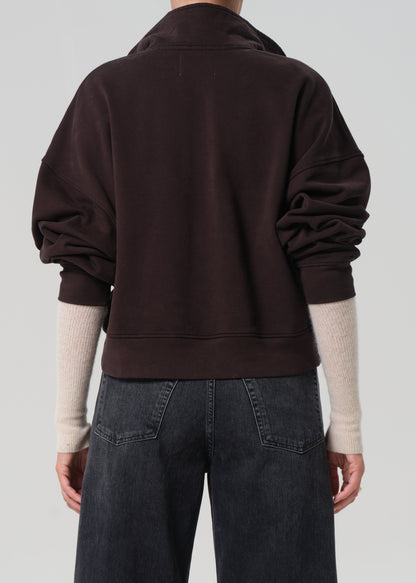 Person wearing a dark brown sweatshirt on a plain background