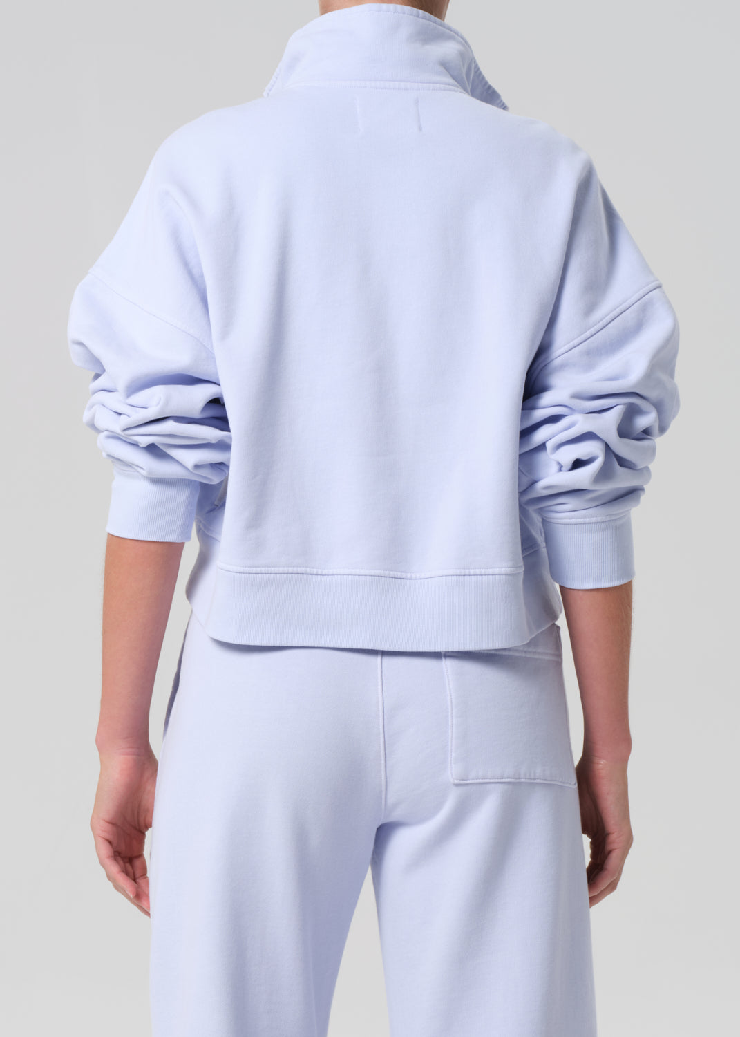 Person wearing a light blue tracksuit against a plain background