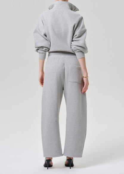 A model shown from the back wearing a light grey heathered sweatshirt and matching wide-leg sweatpants, paired with black pointed-toe heels against a grey background.