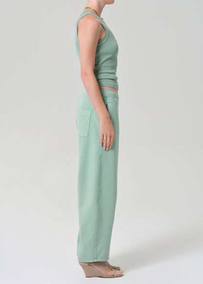 Person wearing a mint green sleeveless tank and matching green sweatpants on a grey background