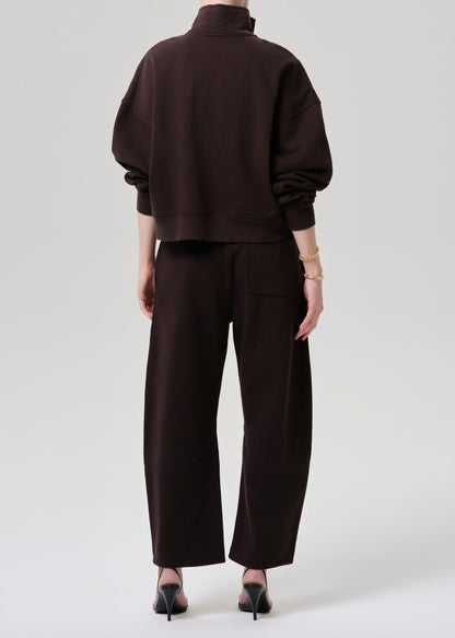 A model shown from the back wearing a dark brown cropped sweatshirt and matching wide-leg trousers, paired with black pointed-toe heels against a grey background.