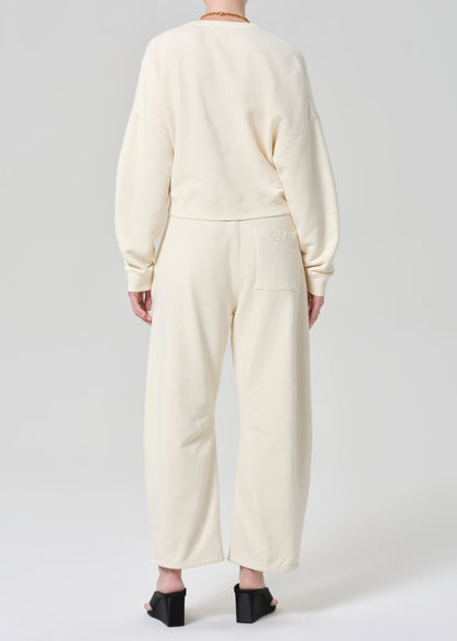 Person wearing a cream sweatshirt with matching cream sweatpants on a grey background