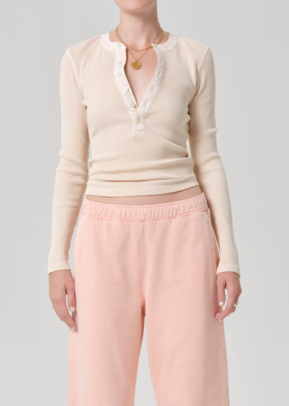 Person wearing a light peach top and pink sweatpants on a grey background