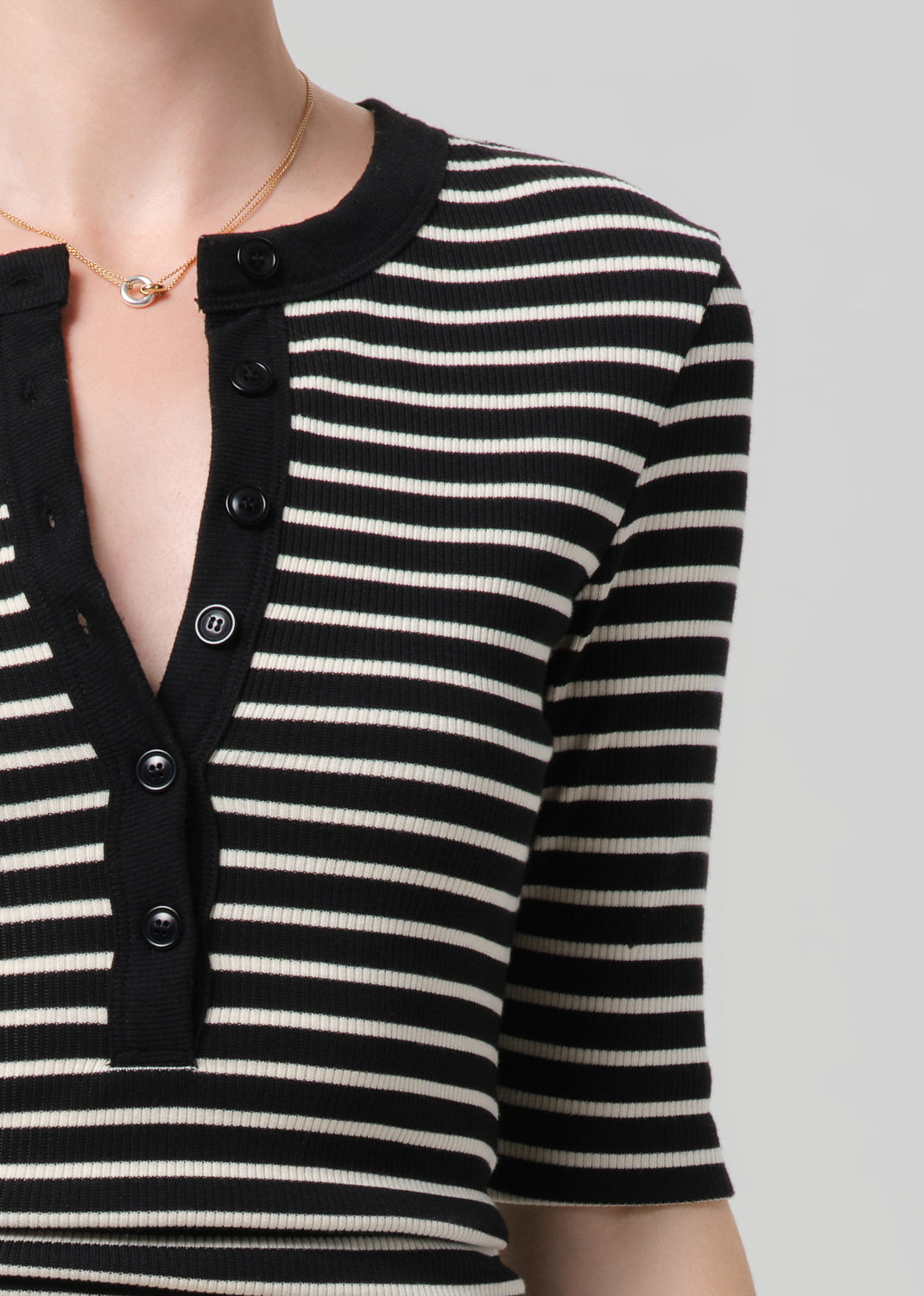 Black and white striped long-sleeve top with buttons on a neutral background