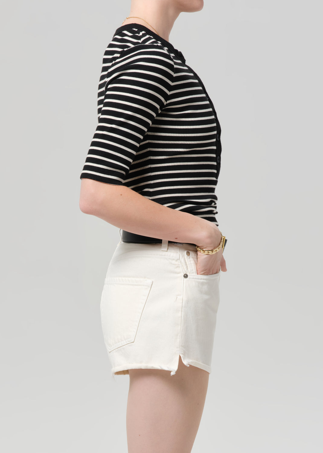 Person wearing a black and white striped shirt and white shorts on a plain background