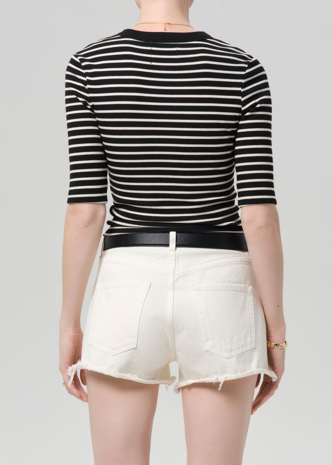Person wearing a black and white striped shirt with white shorts on a gray background
